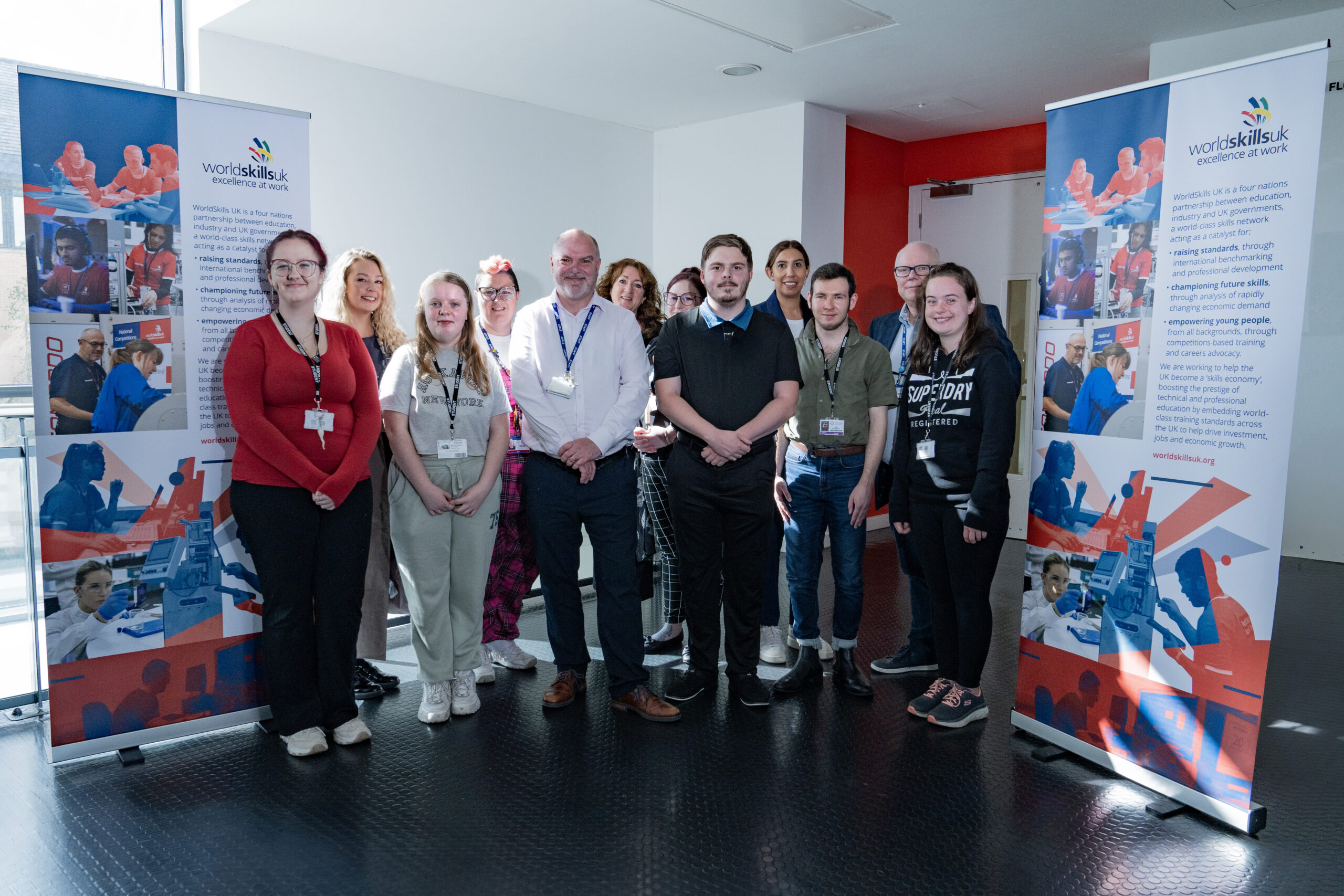 world skills students and teachers stood smiling next to the world skills banners