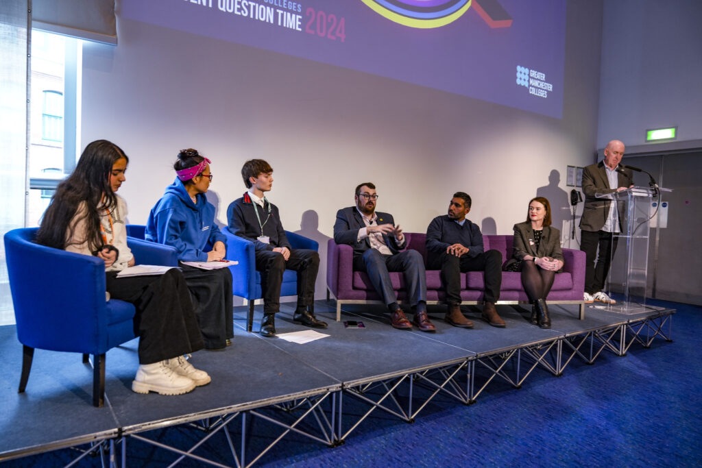 Students sat on a stage having a debate