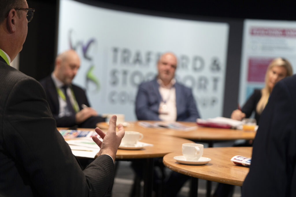 College representatives and visitors seated at a table with coffee cups, engaging in a discussion about education and student development.